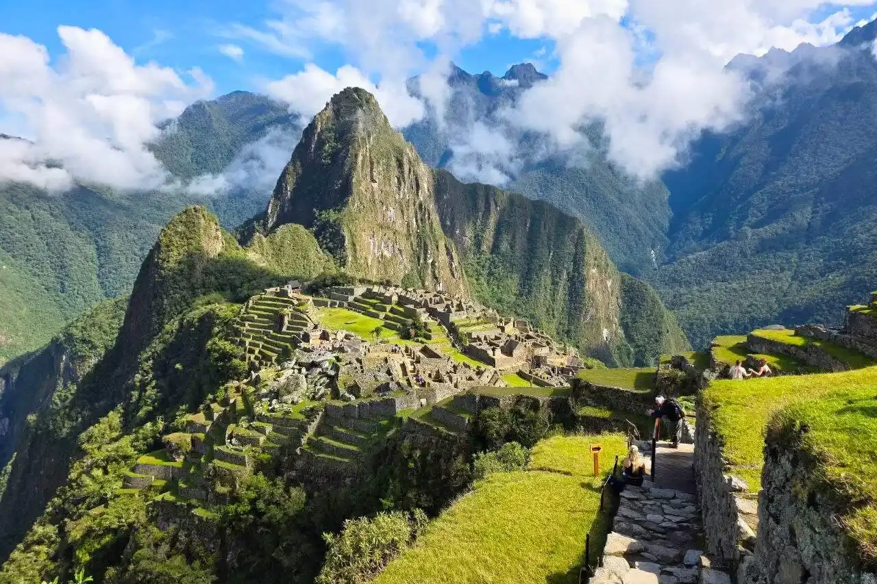An exclusive, personalized private trek on the historic Inca Trail An imposing view of the original stone-paved Inca Trail as it disappears around a steep mountain curve. Llama and other ancient agricultural terraces are visible, illustrating the path of the Inca royalty.