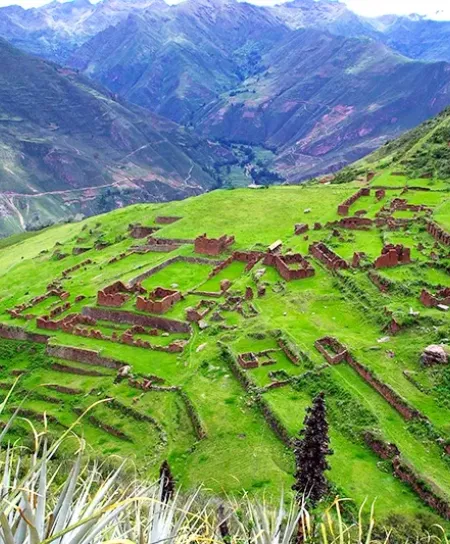 Majestic Ruins of Huchuy Qosqo High-angle view of the Huchuy Qosqo stone structures and green terraces overlooking the deep canyons of the Sacred Valley.